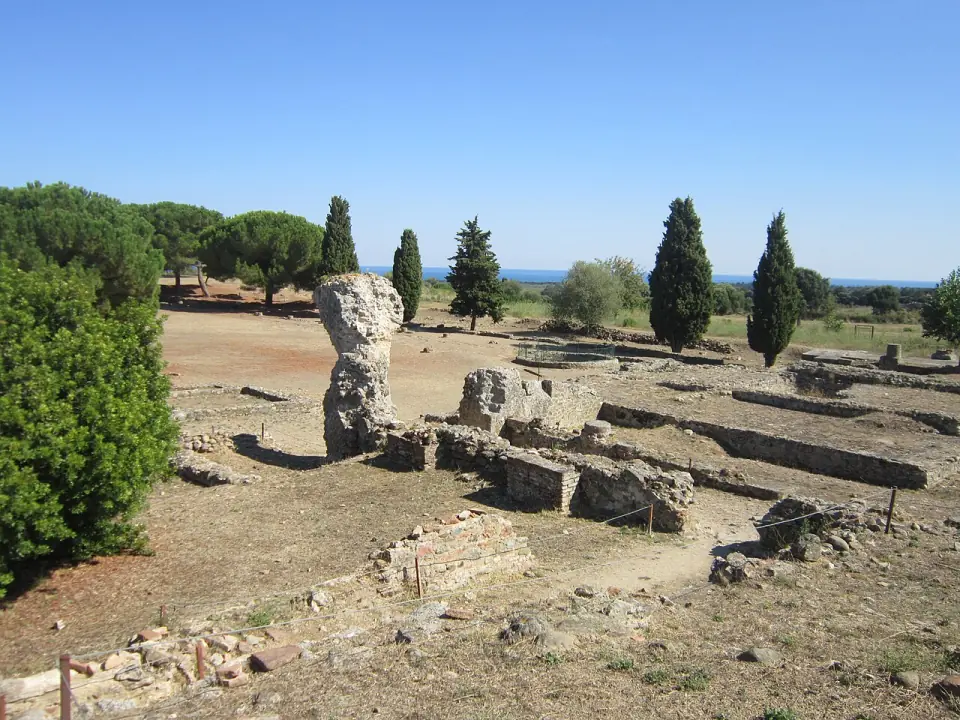 Fût de colonne et murs de pierre sur le site archéologique d'Aléria, avec la mer à l'horizon