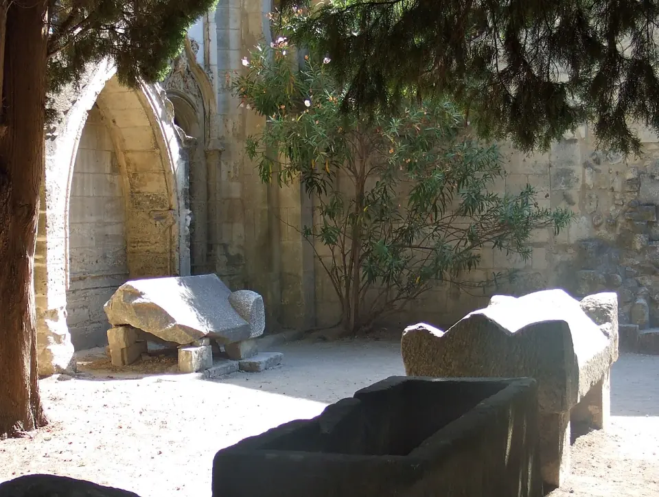 Sarcophages devant les arcades ruinées d'une église des Alyscamps, avec un laurier-rose