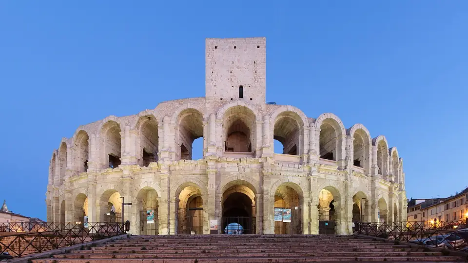 Façade des arènes d'Arles et sa tour médiévale, à la tombée de la nuit