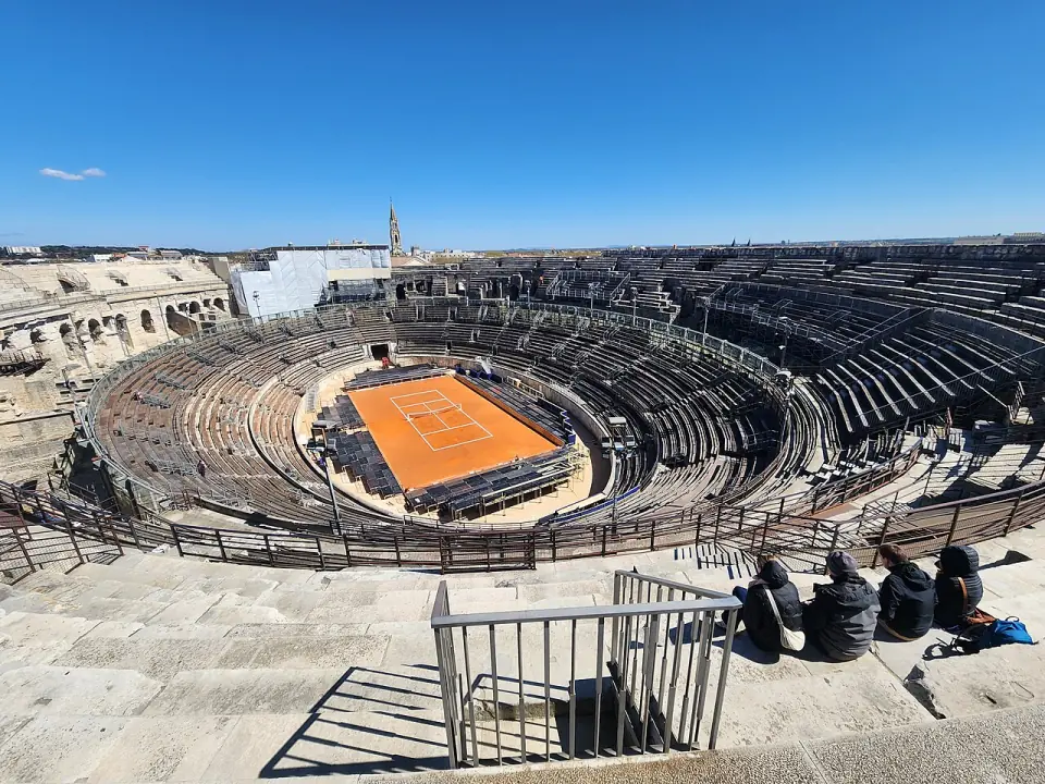 Gradins des arènes de Nîmes vus d'en haut, avec la piste aménagée en court de tennis