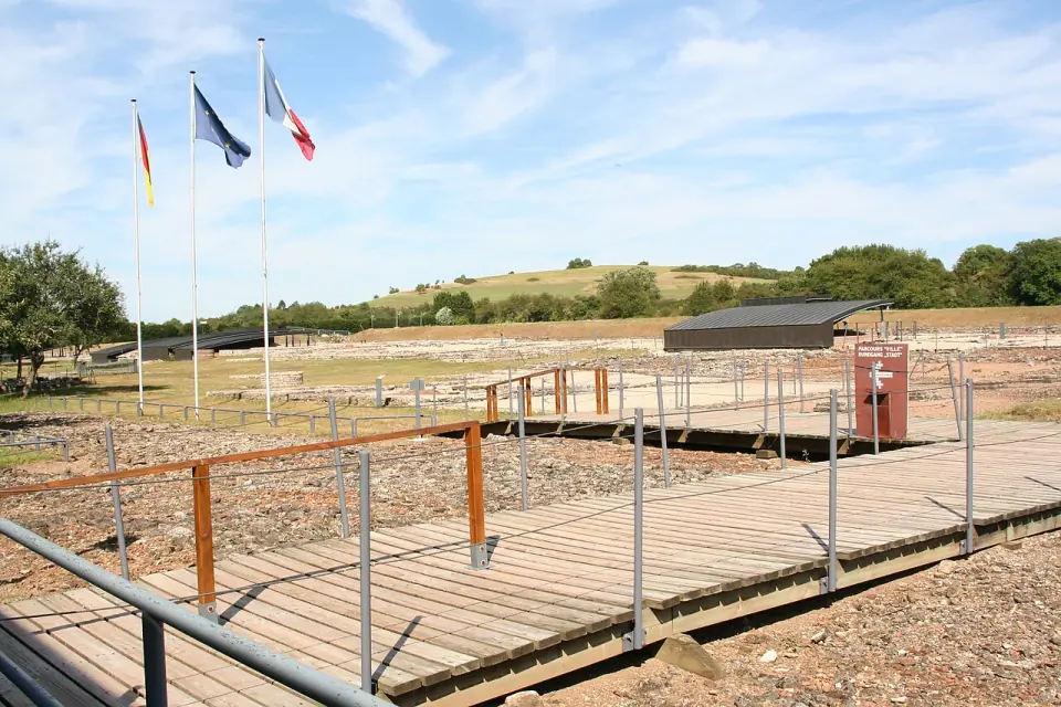 Passerelle de bois au-dessus des vestiges de Bliesbruck, avec les drapeaux français, européen et allemand