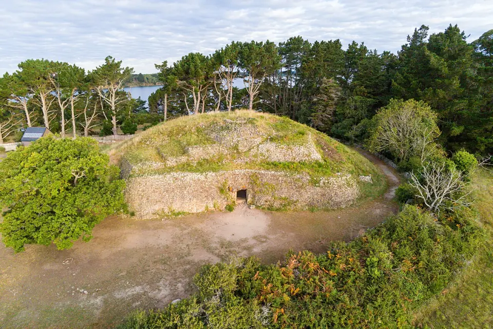 Vue aérienne de la face sud du cairn de Gavrinis, entouré de végétation et d'arbres