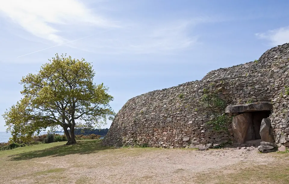 L'entrée du cairn de Gavrinis, avec ses dalles de pierre, et un arbre au premier plan