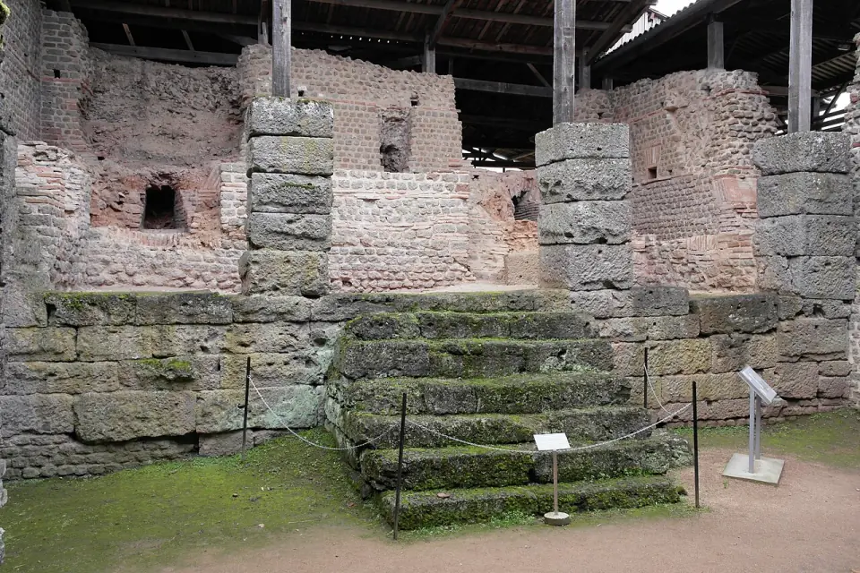 Escalier de pierre moussu devant les murs de briques des thermes gallo-romains de Chassenon