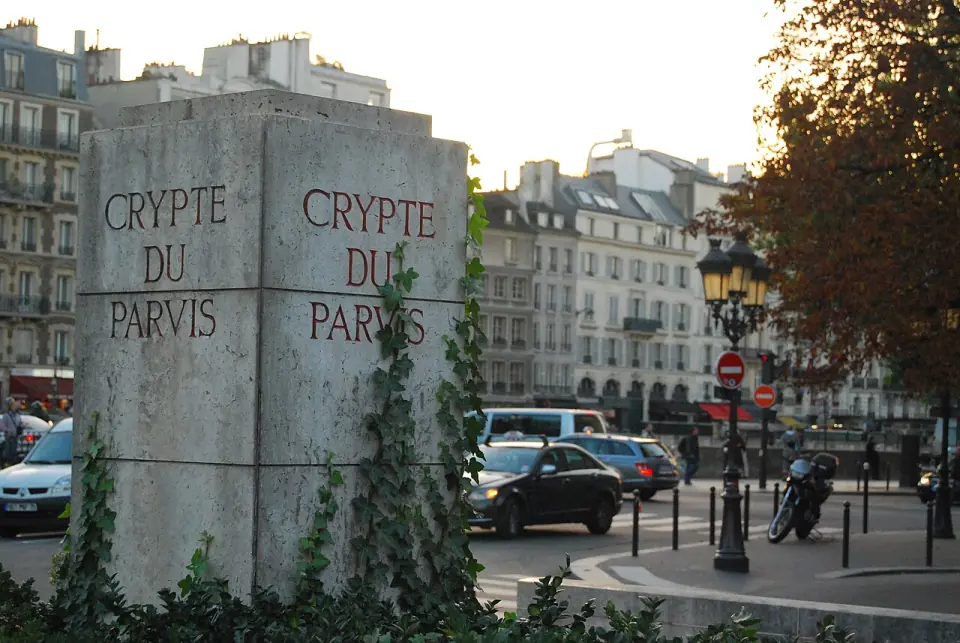 Pylône « Crypte du parvis » sur la place Jean-Paul II, avec des immeubles parisiens au fond