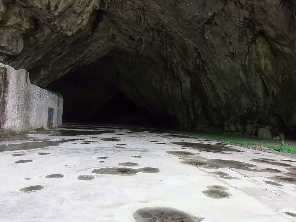 Sous le porche de la grotte de Bédeilhac : sol bétonné, voûte de calcaire et galerie qui s'enfonce dans l'ombre