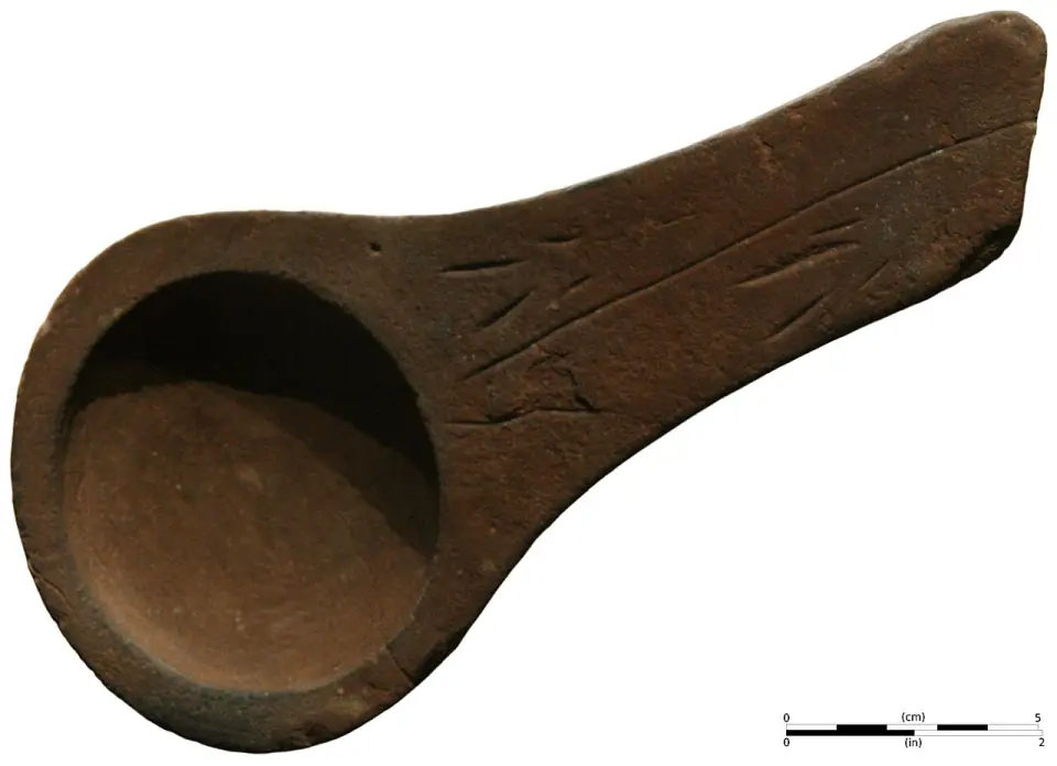 Lampe à graisse en grès rose au manche gravé de traits, découverte à Lascaux