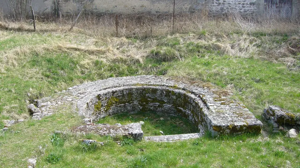 Piscine froide en pierre des thermes de l'ouest d'Anderitum, à Javols, au milieu de l'herbe
