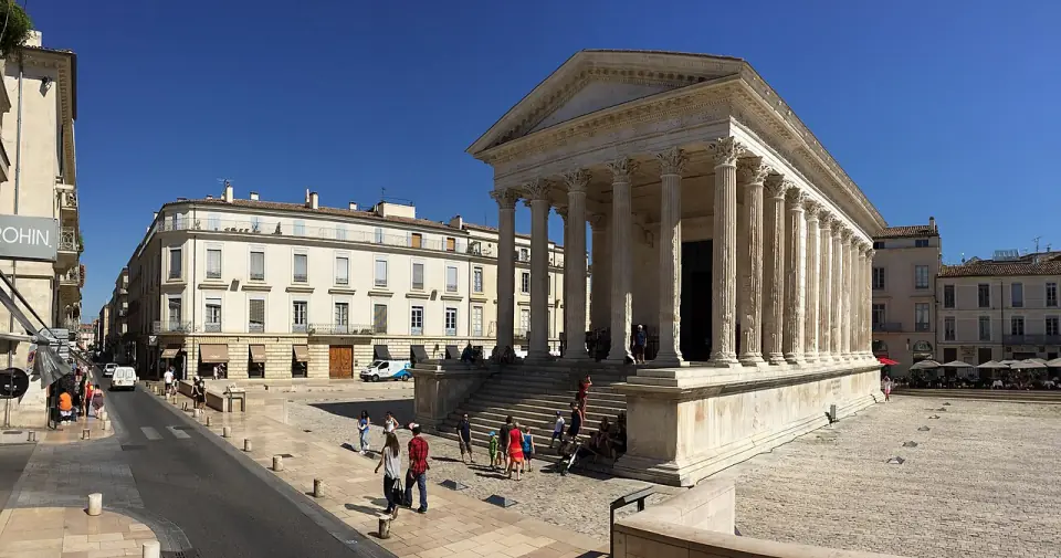 La Maison Carrée de Nîmes en plein jour, sur sa place, avec des passants devant le temple