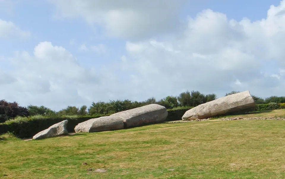 Les quatre fragments du Grand Menhir brisé d'Er Grah, allongés sur l'herbe sous un ciel nuageux
