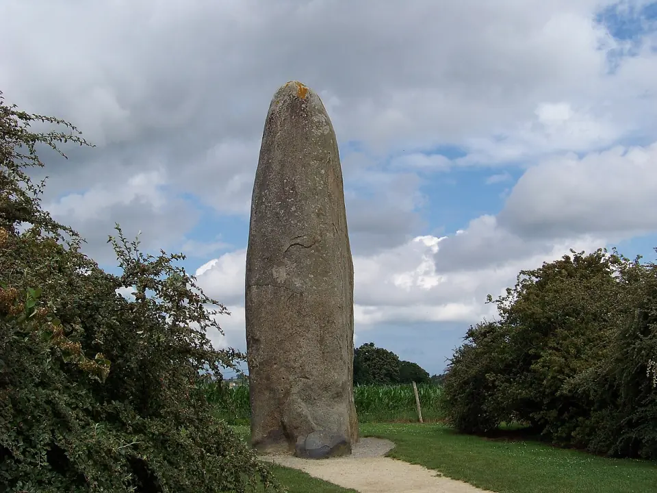 Le menhir de Champ-Dolent dressé au milieu de la campagne, sous un ciel nuageux