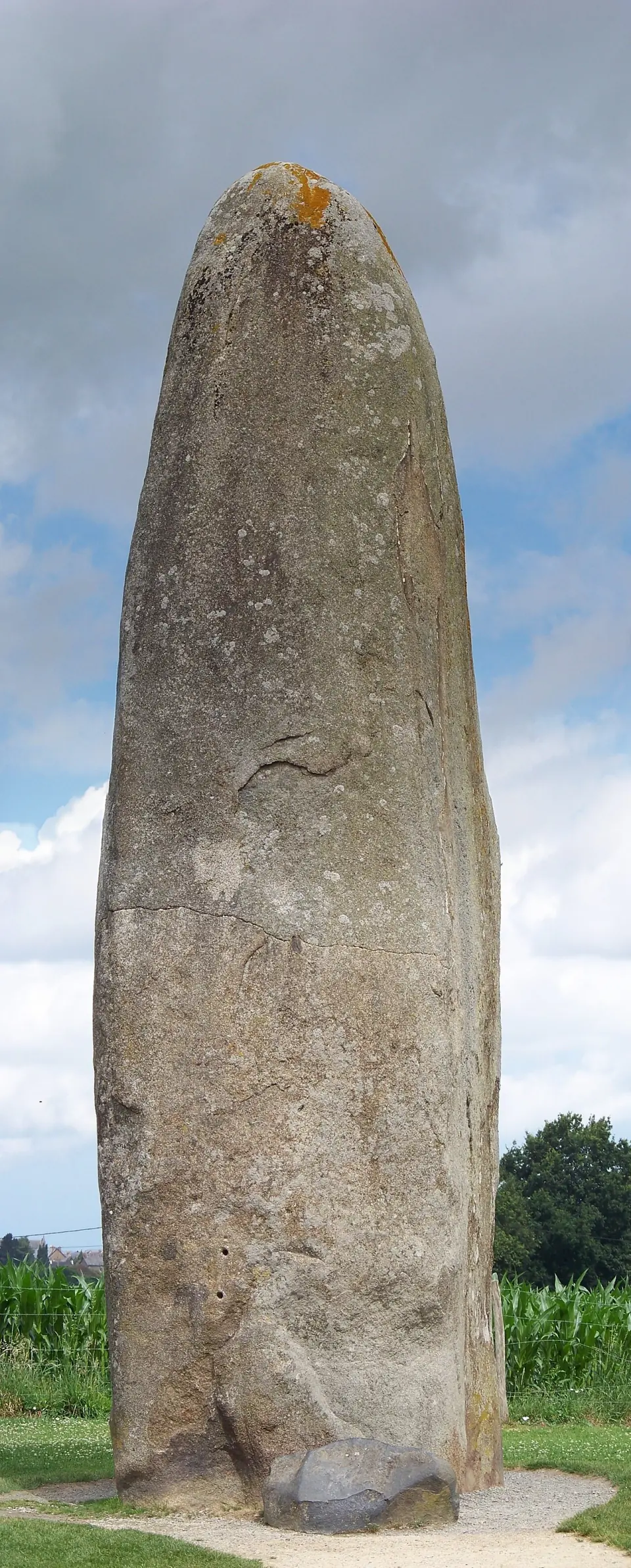 Le menhir de Champ-Dolent en vue verticale, sur fond de ciel et de champs