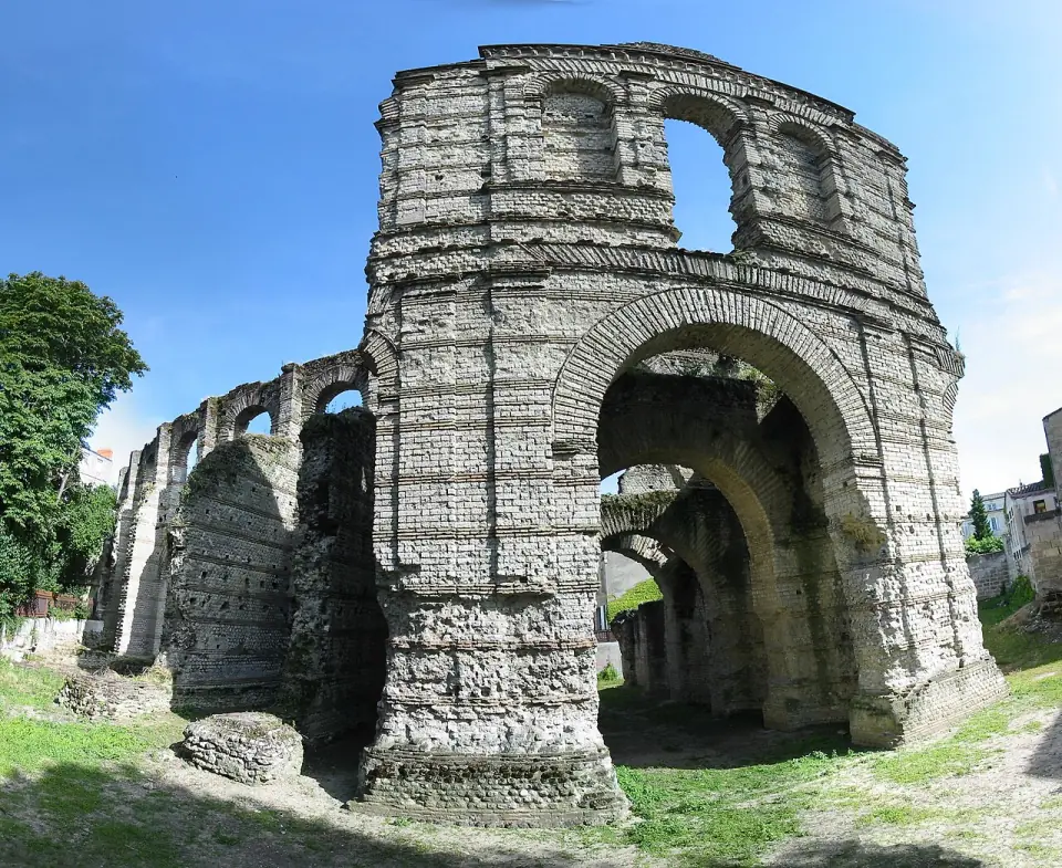 Porte monumentale et arcades du palais Gallien à Bordeaux, en pierre et brique, sous un ciel bleu
