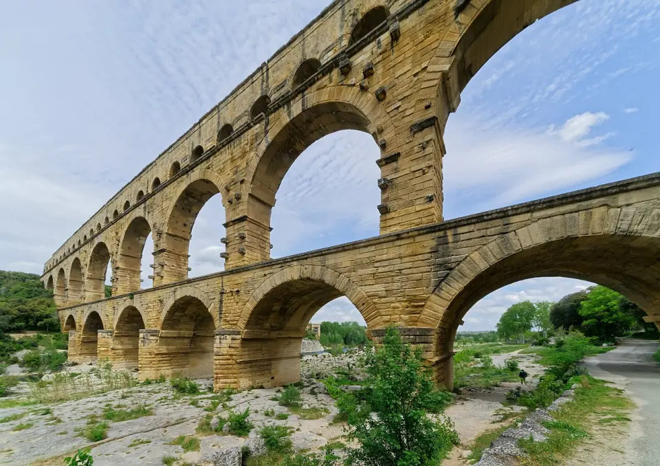 Les arches du Pont du Gard en perspective, vues de la berge, avec le sentier au premier plan