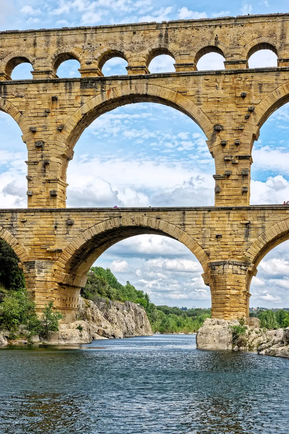 Détail des arches superposées du Pont du Gard, en cadrage vertical, au-dessus de la rivière