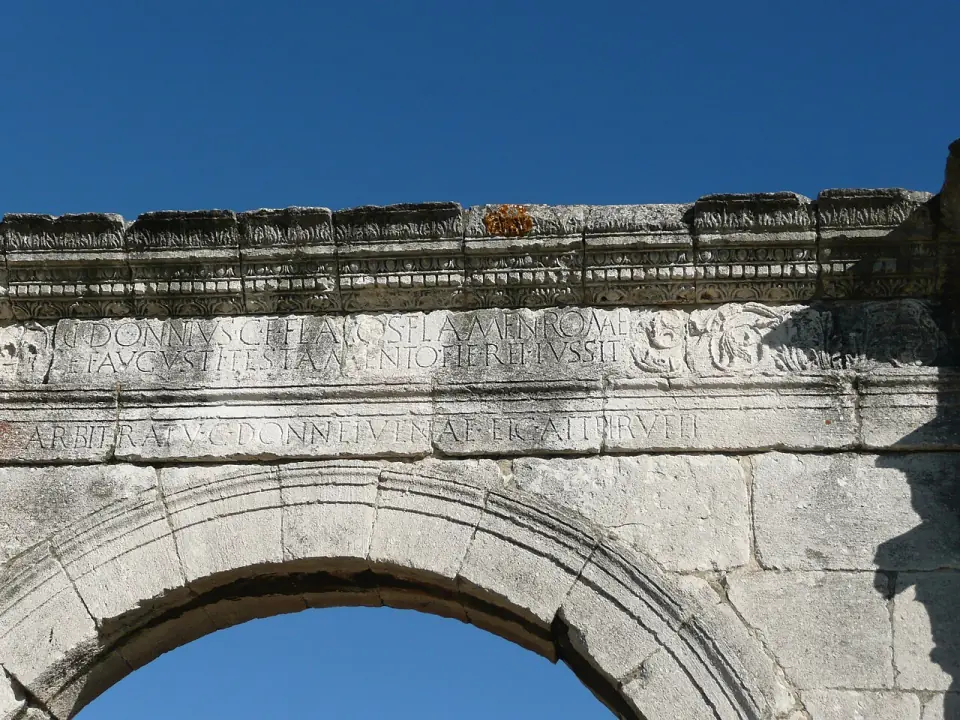 Inscription latine gravée sur la frise d'un arc du pont Flavien, sous un ciel bleu