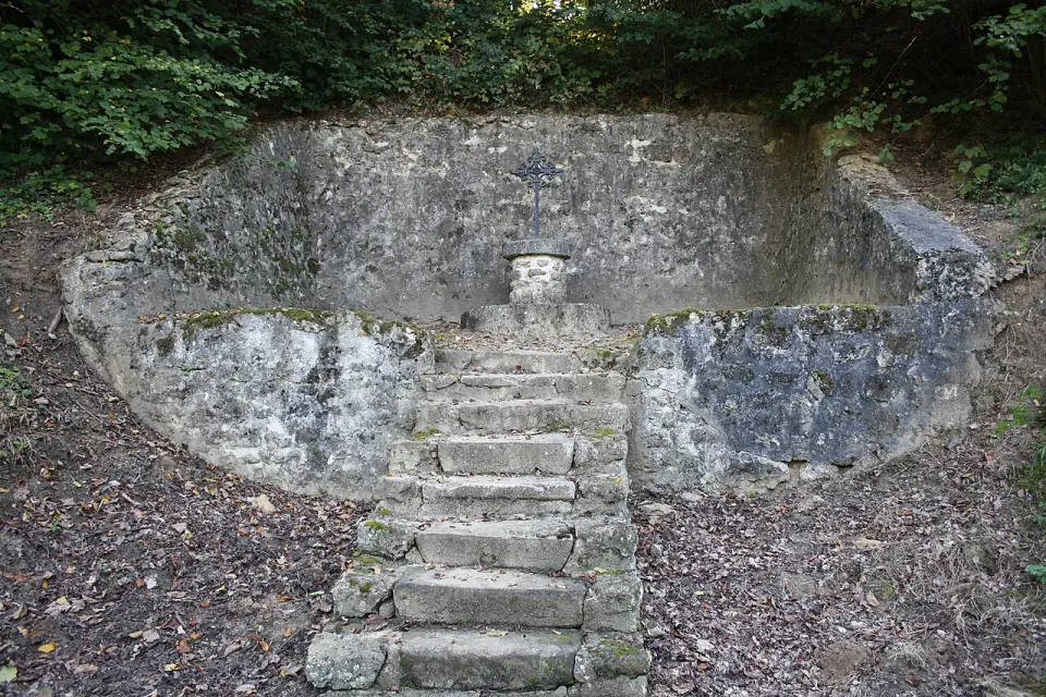 Escalier de pierre menant à un mur en hémicycle, parmi la verdure du domaine