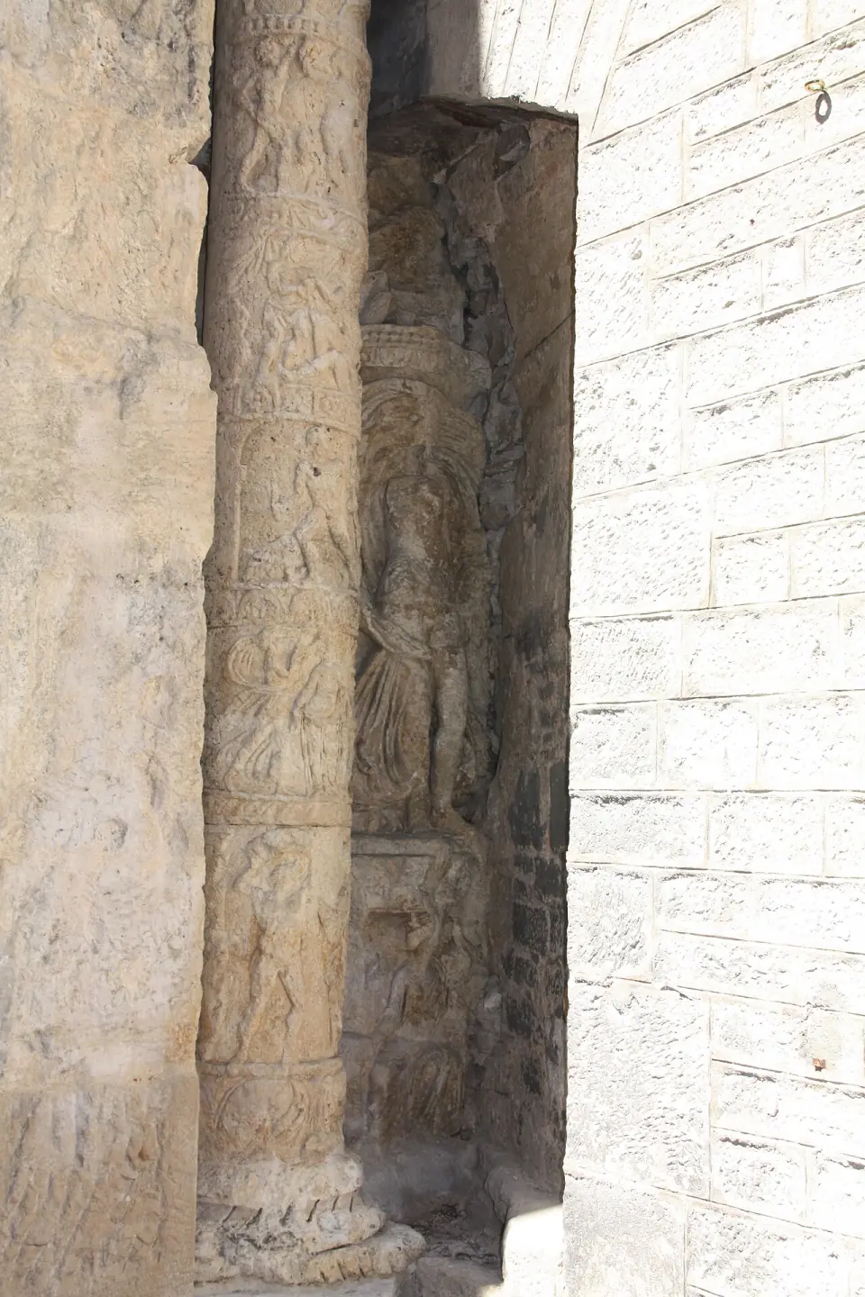 Colonne sculptée de scènes en bas-relief et niche abritant une statue très abîmée, sur la porte Noire