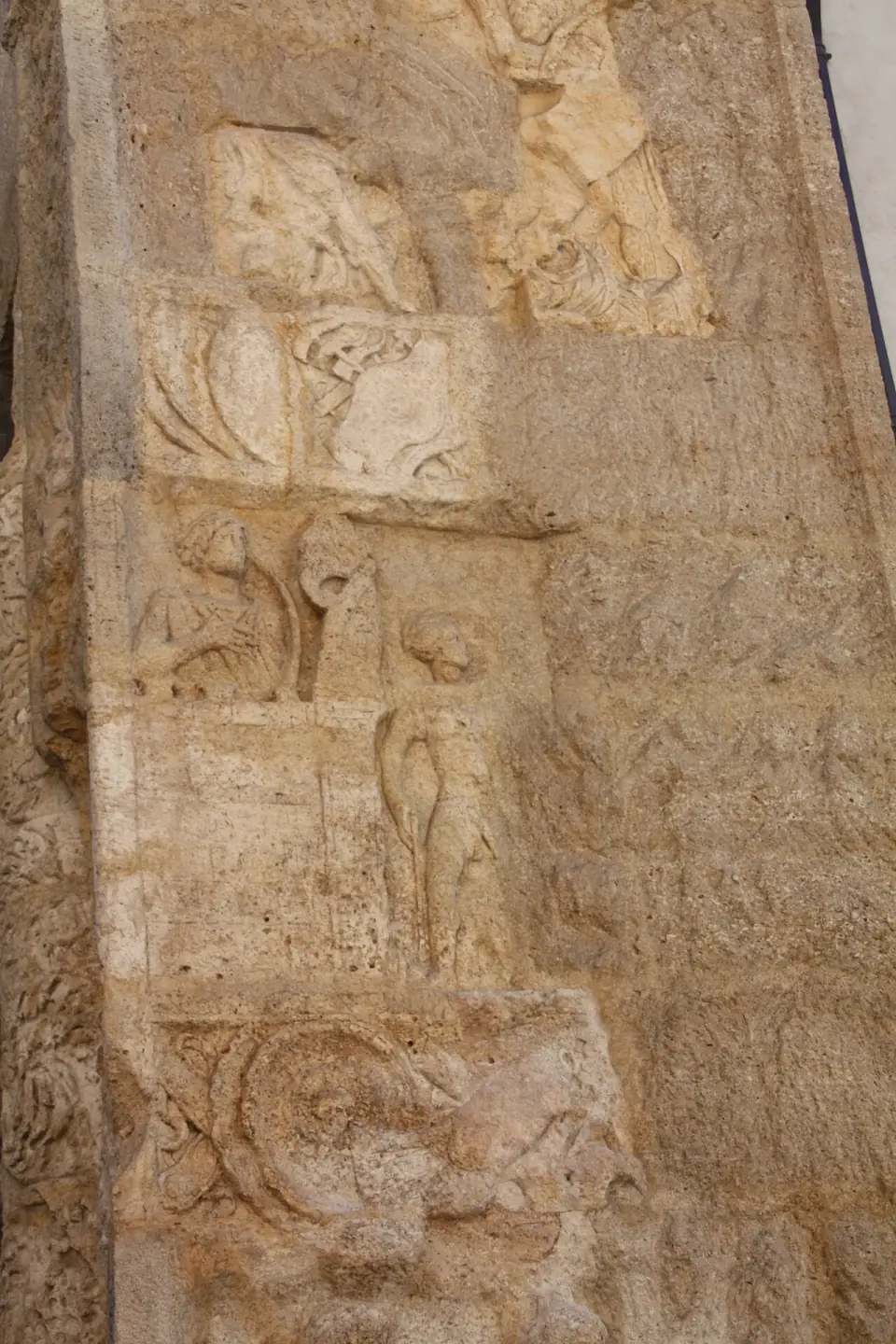 Reliefs usés sur un pilier de la porte Noire : petits personnages et motifs d'ornement sculptés dans la pierre