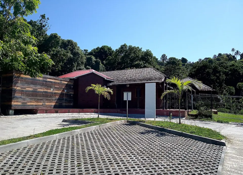 Bâtiment en bois du parc archéologique des Roches gravées, entouré de végétation tropicale, à Trois-Rivières