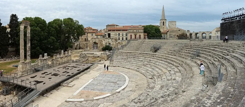 Vue panoramique du théâtre antique d'Arles : gradins en demi-cercle, orchestre dallé et deux colonnes