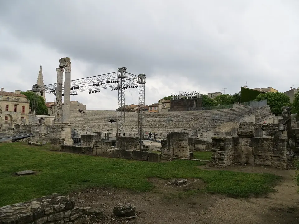 Les deux colonnes du théâtre antique d'Arles au-dessus des vestiges de la scène, avec un clocher en arrière-plan