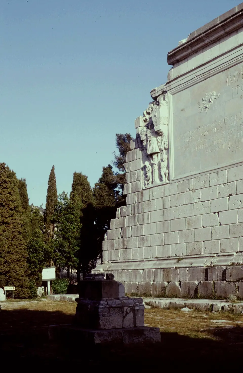 Haut mur du Trophée d'Auguste à La Turbie et ses reliefs sculptés, avec des cyprès