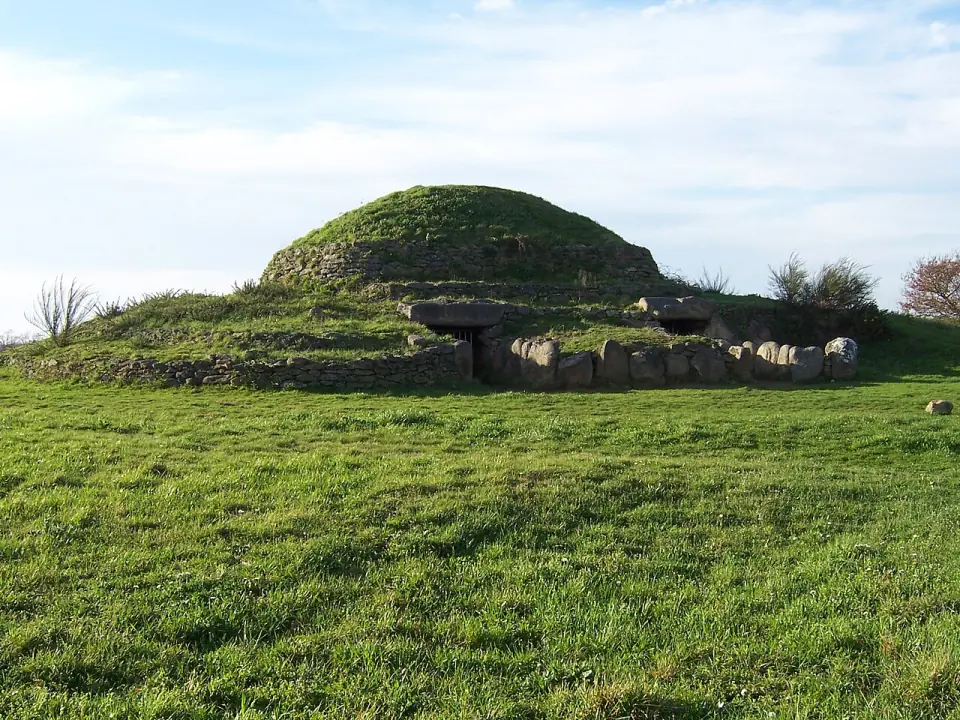 Les deux entrées du tumulus de Dissignac sous leurs dalles, au pied d'une butte herbeuse étagée de murets