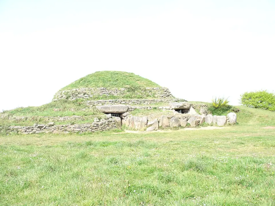 Le tumulus de Dissignac dans la prairie, avec ses murets de pierre et ses blocs dressés devant les entrées