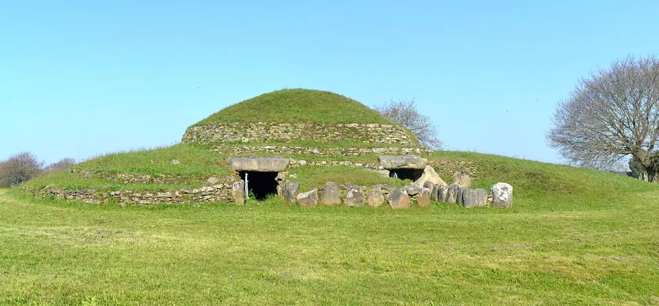 Le tumulus de Dissignac vu de face : butte herbeuse, murets de pierre et deux entrées sous des dalles
