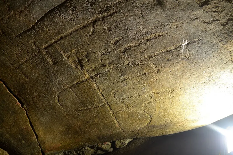 Dalle de plafond gravée à l'intérieur du tumulus de Dissignac, éclairée de côté : signes piquetés dans la roche