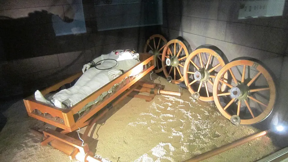 Reconstitution de la tombe de Vix : la défunte allongée sur son char aux roues démontées